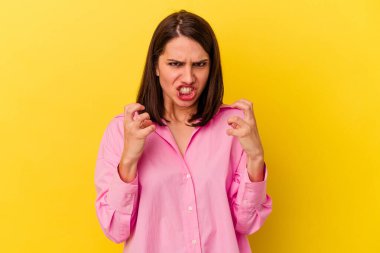 Sarı arka planda izole edilmiş genç beyaz kadın gergin elleriyle çığlık atıyor..