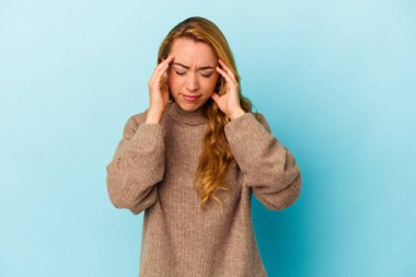 Beyaz kadın mavi arka planda izole edilmiş tapınaklara dokunuyor ve baş ağrısı çekiyor..