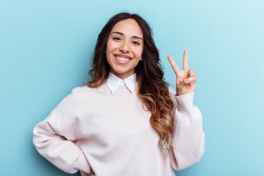 Mavi arka planda izole edilmiş genç Meksikalı kadın iki numarayı parmaklarıyla gösteriyor..