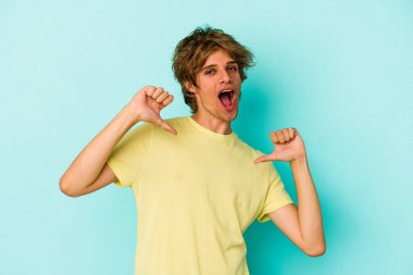 Mavi arka planda soyutlanmış beyaz makyajlı genç bir adam gururlu ve kendinden emin hissediyor, örnek olarak..