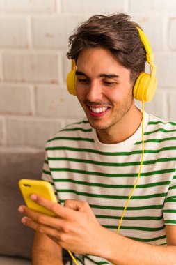 Genç melez adam kanepede oturmuş müzik dinliyor.