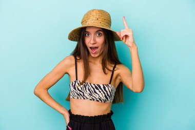 Genç beyaz bir kadın kumsala gidiyor. Mavi arka planda izole edilmiş bikini giyiyor. Bir fikri, ilham verici bir fikri var..