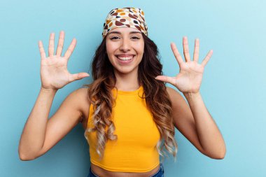 Mavi arka planda izole edilmiş genç Meksikalı kadın on numarayı elleriyle gösteriyor..