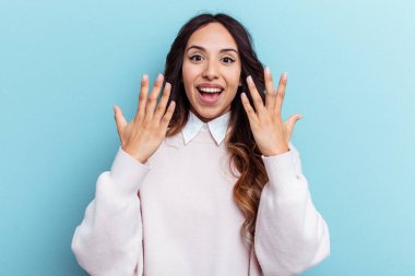 Mavi arka planda izole edilmiş genç Meksikalı kadın on numarayı elleriyle gösteriyor..