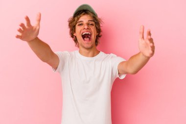 Pembe arka planda soyutlanmış beyaz makyajlı genç bir adam kameraya sarıldığı için kendinden emin hissediyor..