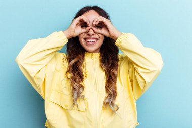 Mavi arka planda izole edilmiş genç Meksikalı kadın gözlerde sorun olmadığını gösteriyor.