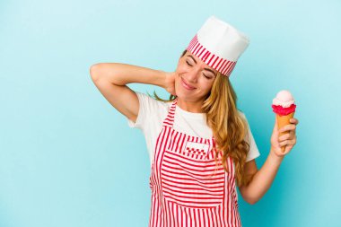 Kafkasyalı dondurma üreticisi kadın elinde dondurma tutuyor mavi arka planda izole edilmiş kafasının arkasına dokunuyor, düşünüyor ve bir seçim yapıyor..