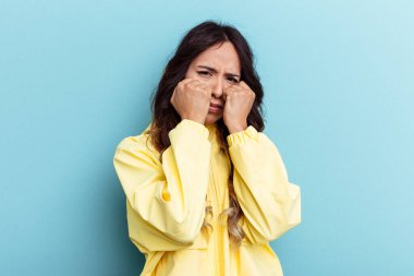 Mavi arka planda izole edilmiş genç Meksikalı kadın bir tartışma yüzünden yumruk, öfke ve kavga atıyor..