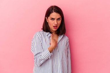 Pembe arka planda soyutlanmış beyaz bir kadın. Parmakla göstererek şaşırmış, geniş bir gülümsemeyle..