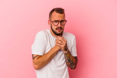 Pembe arka planda izole edilmiş dövmeleri olan genç beyaz adam korkmuş ve korkmuş..