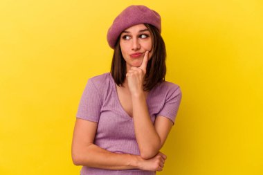 Kafkasyalı genç bir kadın, sarı arka planda izole edilmiş. Bir strateji planlıyor, bir işin nasıl olacağını düşünüyor..