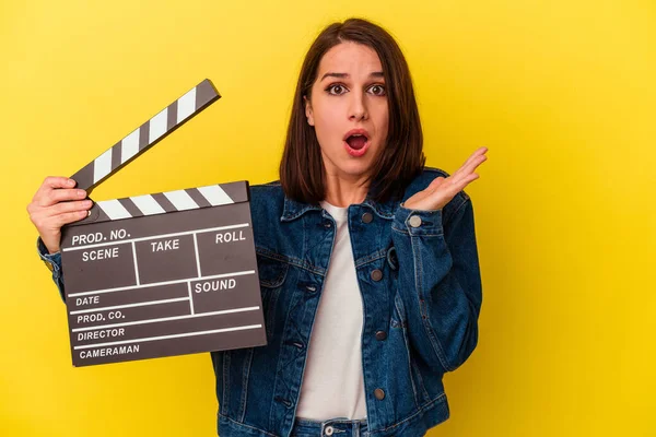 Young Caucasian Woman Holding Clapperboard Isolated Yellow Background Surprised Shocked — Stock Photo, Image
