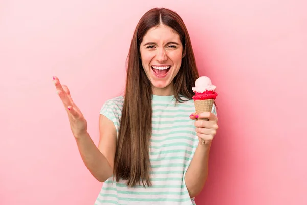 ピンクの背景に隔離されたアイスクリームを持つ若い白人女性は 楽しい驚き 興奮し 手を上げます — ストック写真