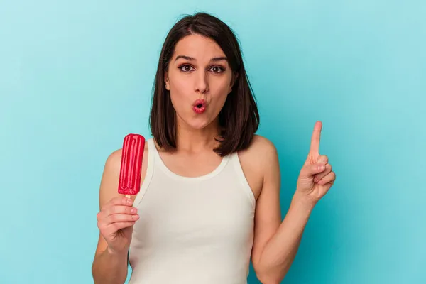 青い背景に隔離されたアイスクリームを持つ若い白人女性は素晴らしいアイデア 創造性の概念を持っています — ストック写真