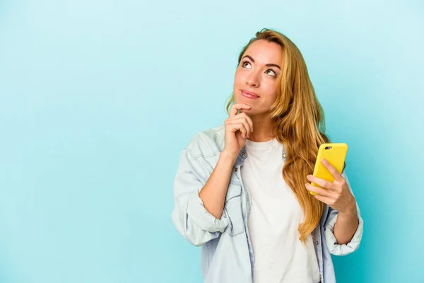 Mujer Caucásica Sosteniendo Teléfono Móvil Aislado Sobre Fondo Azul Mirando —  Fotos de Stock