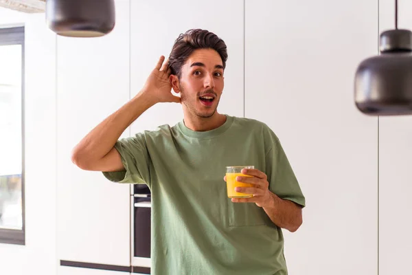 Joven Hombre Raza Mixta Bebiendo Jugo Naranja Cocina Tratando Escuchar — Foto de Stock