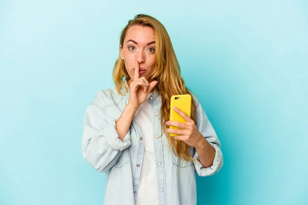 Mulher Caucasiana Segurando Celular Isolado Fundo Azul Mantendo Segredo Pedindo — Fotografia de Stock