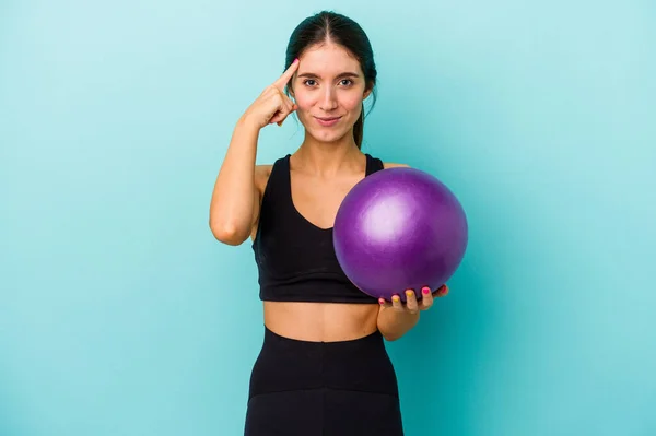 Jonge Blanke Fitnessvrouw Met Een Bal Geïsoleerd Blauwe Achtergrond Wijzende — Stockfoto