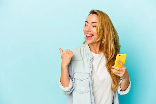 Běloška Drží Mobilní Telefon Izolovaný Modrém Pozadí Palcem Pryč Směje — Stock fotografie