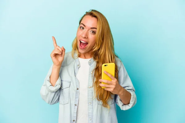 Donna Caucasica Possesso Telefono Cellulare Isolato Sfondo Blu Avendo Idea — Foto Stock
