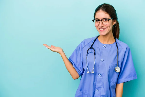 Jonge Blanke Verpleegster Geïsoleerd Blauwe Achtergrond Toont Een Kopieerruimte Een — Stockfoto