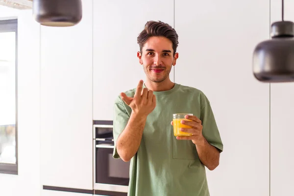 Joven Hombre Raza Mixta Bebiendo Jugo Naranja Cocina Señalándote Con — Foto de Stock