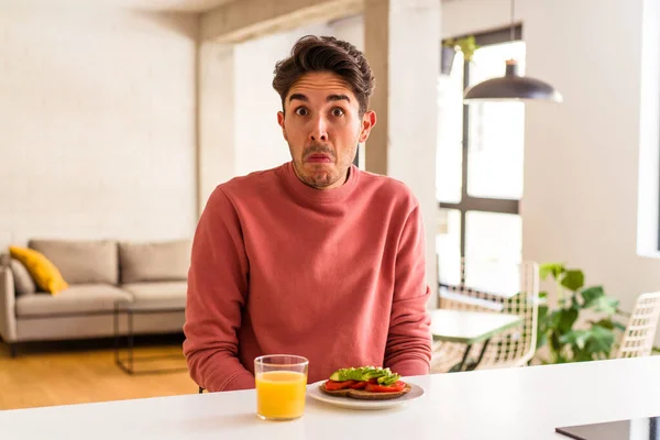 Joven Hombre Raza Mixta Desayunando Cocina Encoge Hombros Los Ojos — Foto de Stock