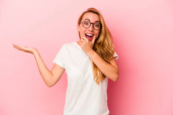 Blanke Blonde Vrouw Geïsoleerd Roze Achtergrond Houdt Kopieerruimte Een Handpalm — Stockfoto