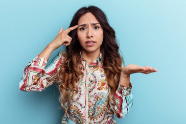 Mavi arka planda izole edilmiş genç Meksikalı kadın işaret parmağıyla hayal kırıklığı jesti gösteriyor..