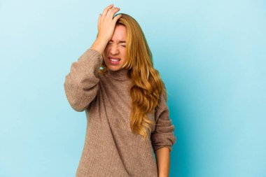 Beyaz kadın mavi arka planda izole edilmiş bir şekilde bir şeyi unutuyor. Alnına avuç içi ve kapalı gözlerle vuruyor..