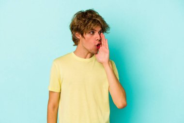 Mavi arka planda izole edilmiş beyaz makyajlı genç bir adam gizli bir sıcak fren haberi veriyor ve yan bakıyor.