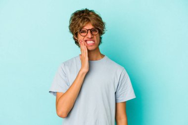 Makyajlı beyaz bir adam mavi arka planda izole edilmiş güçlü bir diş ağrısı, azıdişi ağrısı var..