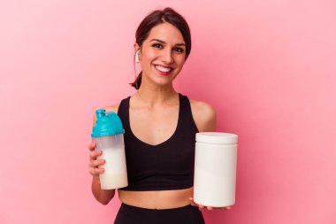 Pembe arka planda izole edilmiş protein içeceği içen beyaz bir kadın.
