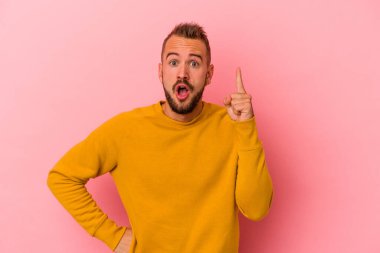 Pembe arka planda izole edilmiş dövmeleri olan genç beyaz bir adam. Bir fikri var, ilham verici bir kavram..