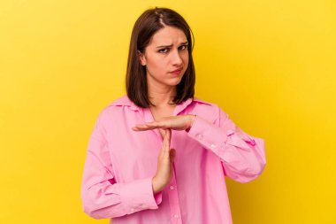 Sarı arka planda izole edilmiş genç beyaz kadın bir mola hareketi gösteriyor..