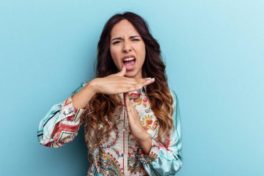 Mavi arka planda izole edilmiş genç Meksikalı kadın bir mola hareketi gösteriyor..