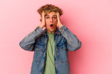 Pembe arka planda mahsur kalmış beyaz makyajlı genç adam şoka uğruyor, önemli bir toplantıyı hatırlıyor..