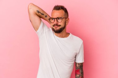 Pembe arka planda izole edilmiş, kafasının arkasına dokunan, düşünen ve bir seçim yapan beyaz bir adam..