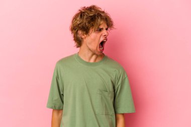 Makyajlı beyaz bir adam pembe arka planda izole edilmiş çok kızgın, öfkeli, hayal kırıklığına uğramış bağırıyor..