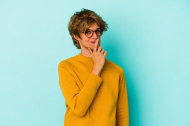 Makyajlı genç beyaz bir adam mavi arka planda izole edilmiş. Bir strateji planlıyor, bir iş yolu düşünüyor..