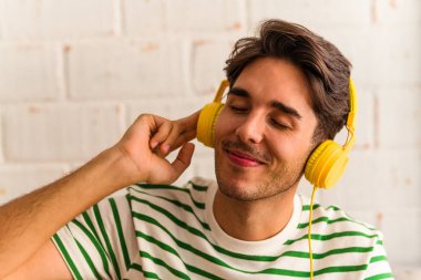 Genç melez adam kanepede oturmuş müzik dinliyor.