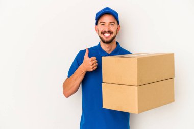 Beyaz arka planda izole edilmiş dövmeleri olan beyaz bir teslimatçı. Gülümsüyor ve başparmağını kaldırıyor.