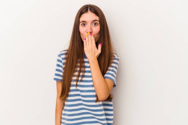 Beyaz arka planda izole edilmiş genç beyaz kadın şok olmuş, elleri ağızda, yeni bir şey keşfetmeye hevesli..