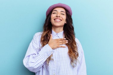 Young mexican woman isolated on blue background laughs out loudly keeping hand on chest. clipart