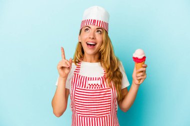Kafkasyalı dondurma üreticisi kadın elinde dondurma tutuyordu. Mavi arka planda izole edilmiş ve ağzı açık bir şekilde yukarı bakıyordu..