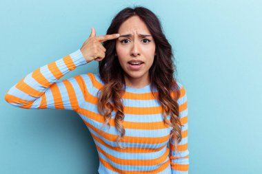 Mavi arka planda izole edilmiş genç Meksikalı kadın işaret parmağıyla hayal kırıklığı jesti gösteriyor..