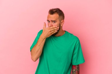 Pembe arka planda izole edilmiş, ağzı kapalı elleri endişeli görünen beyaz bir adam..