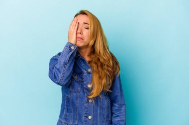 Kafkasyalı bir kadın mavi arka planda izole edilmiş. Çok yorgun ve uykulu. Elini başının üstünde tutuyor..