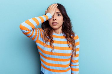Mavi arka planda izole edilmiş genç Meksikalı kadın bir şeyi unutuyor. Alnına avuç içi ve kapalı gözlerle vuruyor..