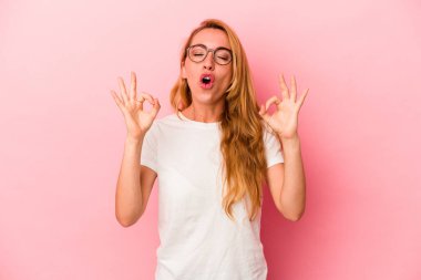 Kafkasyalı sarışın kadın pembe arka planda izole edilmiş yoğun çalışma gününden sonra rahatlıyor, yoga yapıyor..